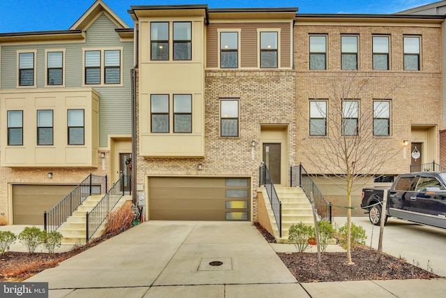 multi unit property featuring brick siding, concrete driveway, and an attached garage