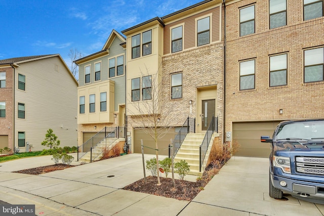 townhome / multi-family property featuring an attached garage, concrete driveway, and brick siding