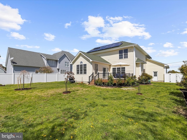 1121 Old Love Point Rd, Stevensville, MD 21666 - rear view of property featuring a lawn, roof mounted solar panels, fence, and a deck