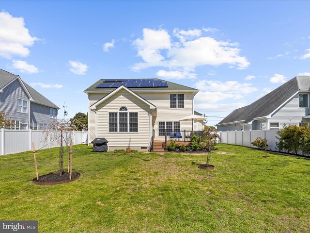 1121 Old Love Point Rd, Stevensville, MD 21666 - rear view of house featuring roof mounted solar panels, a lawn, a fenced backyard, and a deck
