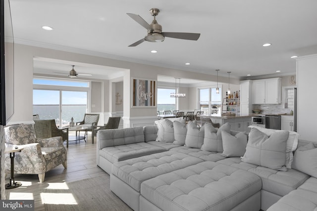 living room with recessed lighting, light wood-style floors, ornamental molding, and a ceiling fan