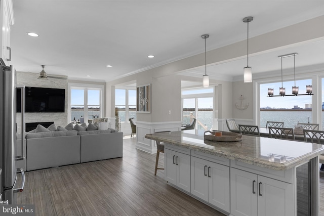 kitchen with open floor plan, wainscoting, crown molding, and a kitchen breakfast bar