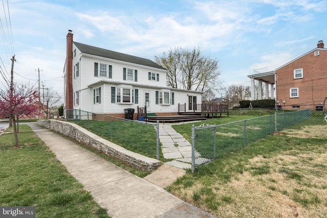 view of front of home with a chimney, fence private yard, a front yard, and a deck