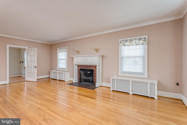 unfurnished living room with ornamental molding, wood finished floors, a brick fireplace, and radiator