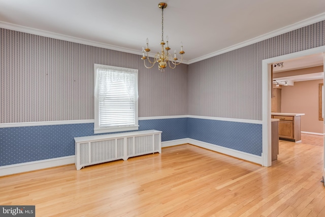 unfurnished room featuring wallpapered walls, wood finished floors, a notable chandelier, and radiator