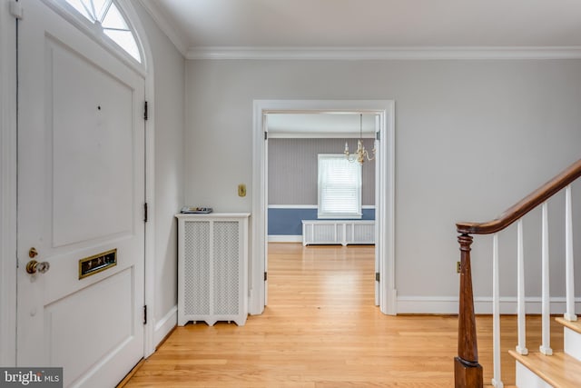 entrance foyer with stairs, crown molding, a chandelier, radiator, and light wood-style flooring