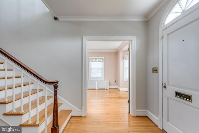 foyer with stairs, ornamental molding, light wood-style flooring, and radiator