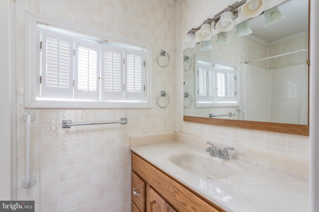 bathroom featuring crown molding, vanity, tile walls, and walk in shower