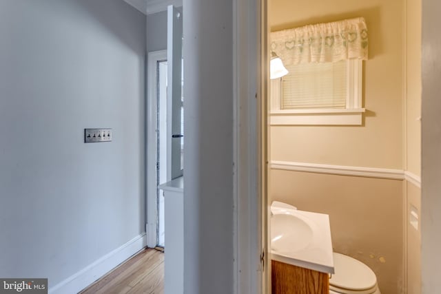 bathroom featuring toilet, vanity, baseboards, and wood finished floors