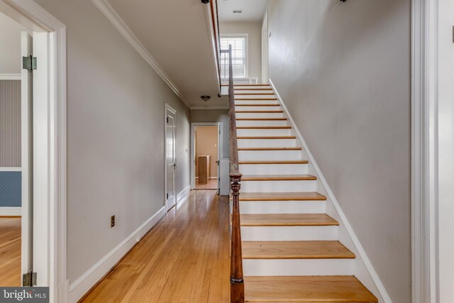 stairway featuring baseboards, wood finished floors, and ornamental molding