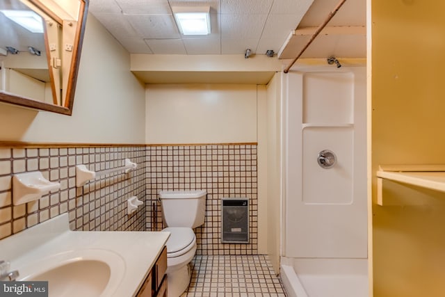 bathroom featuring tile walls, a wainscoted wall, walk in shower, toilet, and heating unit