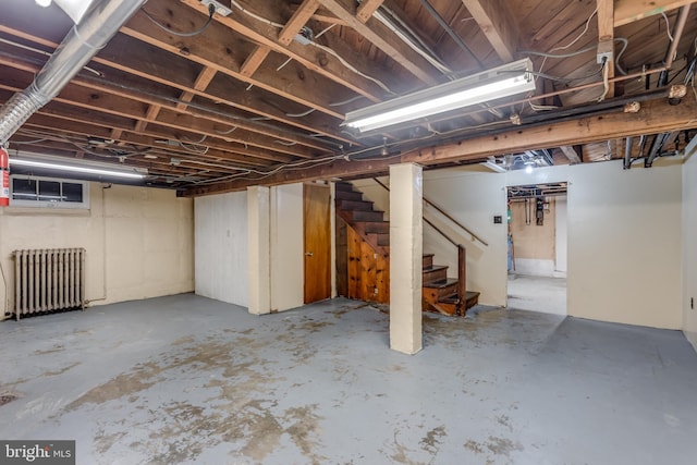 unfinished basement with radiator heating unit and stairway