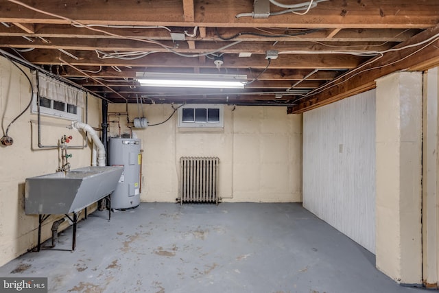 unfinished below grade area with electric water heater and radiator heating unit