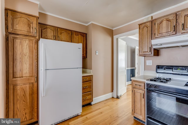 kitchen with crown molding, under cabinet range hood, light wood-type flooring, black gas range, and freestanding refrigerator