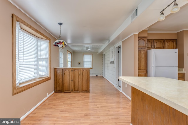 kitchen with light countertops, light wood finished floors, ornamental molding, brown cabinets, and freestanding refrigerator