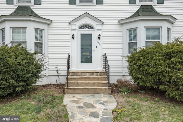 doorway to property with roof with shingles