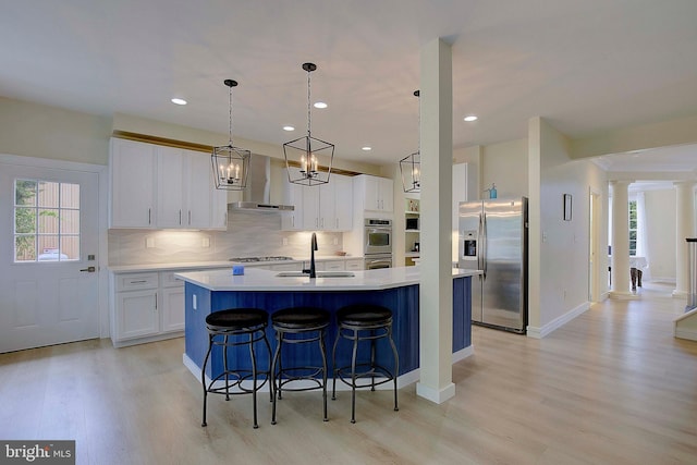 8177 Bodkin Ave, Pasadena, MD 21122 - kitchen with appliances with stainless steel finishes, a sink, light wood-style floors, ornate columns, and wall chimney exhaust hood