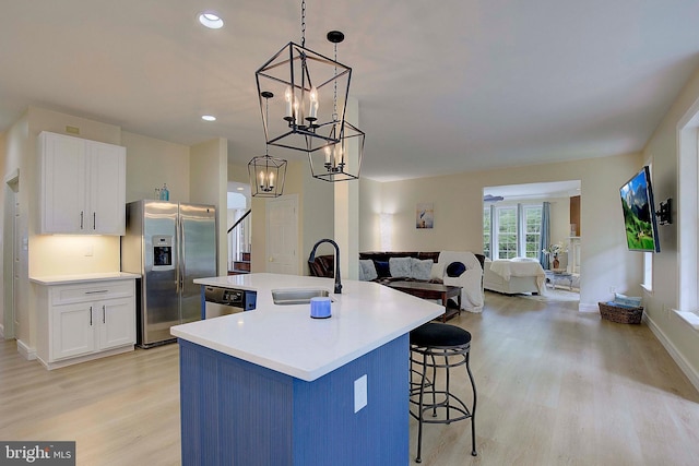 8177 Bodkin Ave, Pasadena, MD 21122 - kitchen featuring a chandelier, white cabinets, a sink, light wood-style flooring, and stainless steel appliances