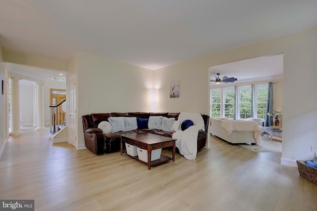 8177 Bodkin Ave, Pasadena, MD 21122 - living room with ornate columns, baseboards, light wood finished floors, and stairs