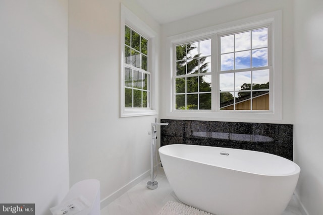 8177 Bodkin Ave, Pasadena, MD 21122 - bathroom with baseboards, marble finish floor, and a freestanding tub