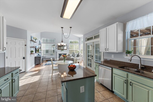 kitchen with stainless steel dishwasher, a sink, open floor plan, green cabinets, and a kitchen island