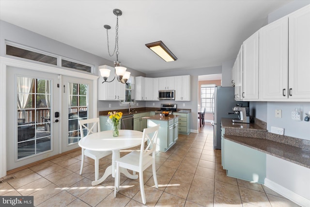 kitchen with dark countertops, a sink, white cabinets, appliances with stainless steel finishes, and a kitchen island