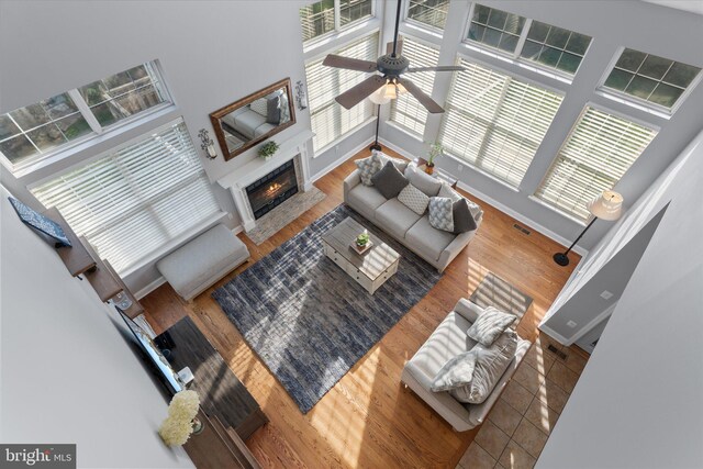 living room with a fireplace with flush hearth, a ceiling fan, visible vents, and plenty of natural light