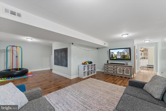 living area featuring baseboards, wood finished floors, and visible vents