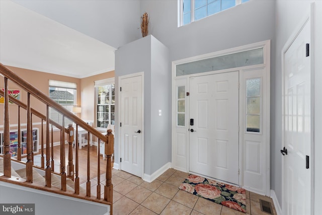 foyer featuring a wealth of natural light, stairs, visible vents, and light tile patterned floors