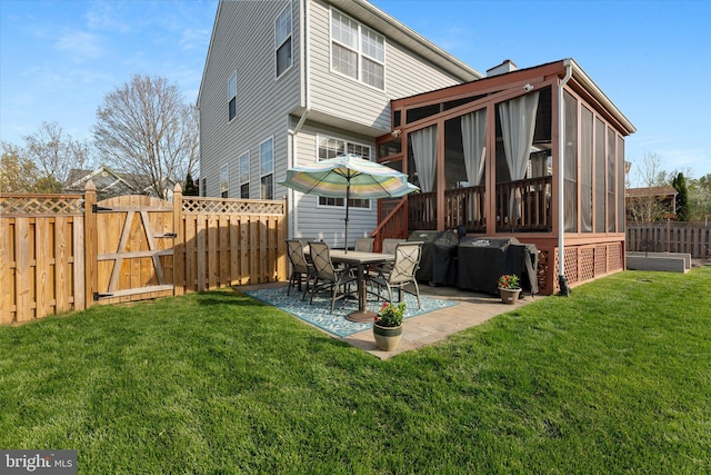 rear view of house with a fenced backyard, a gate, a patio area, a yard, and a sunroom