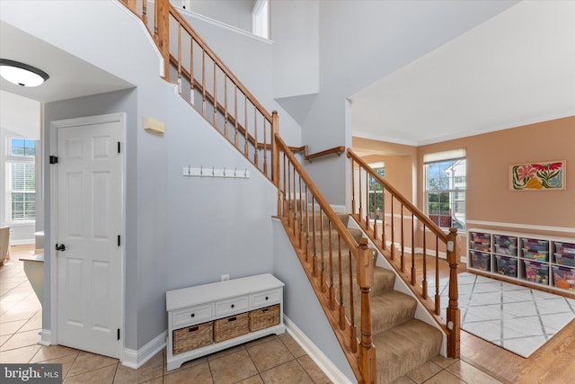 stairway with tile patterned floors, baseboards, and a towering ceiling