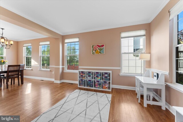 interior space with an inviting chandelier, crown molding, wood finished floors, and baseboards