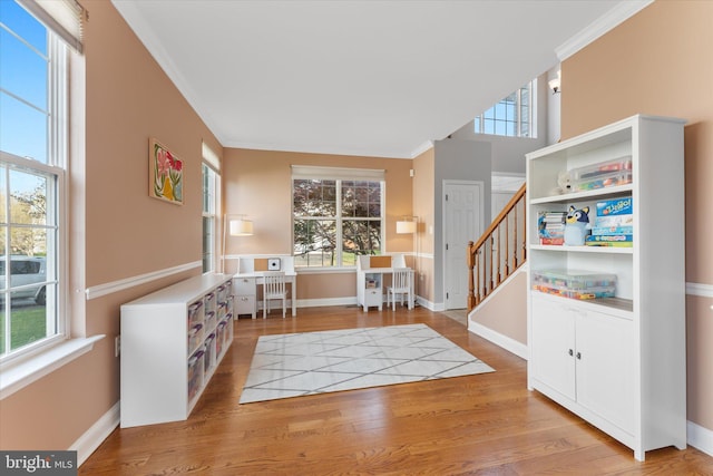 foyer featuring baseboards, ornamental molding, wood finished floors, and stairs
