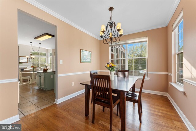 dining space featuring baseboards, crown molding, wood finished floors, and a chandelier