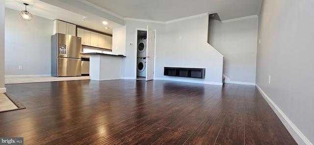 unfurnished living room featuring stacked washer and dryer, dark wood-style flooring, baseboards, and crown molding