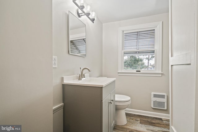 103 Cromwell Ave, Glen Burnie, MD 21061 - half bathroom featuring vanity, toilet, baseboards, heating unit, and wood finished floors