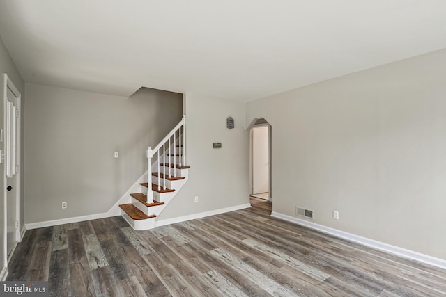 103 Cromwell Ave, Glen Burnie, MD 21061 - unfurnished living room featuring stairway, baseboards, arched walkways, visible vents, and wood finished floors