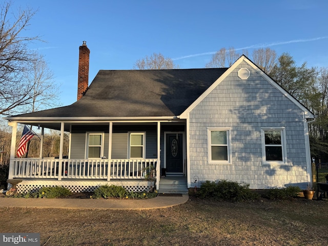 view of front facade featuring a chimney and a porch