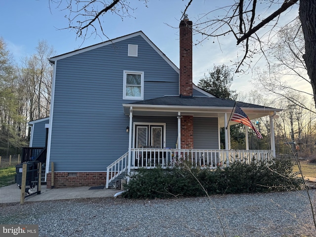 view of front of house with crawl space, covered porch, and a chimney