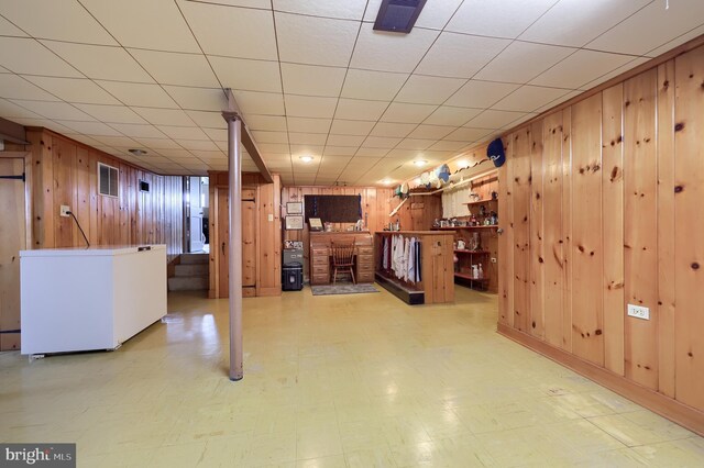 3902 Reiff Pl, Reading, PA 19606 - finished basement with refrigerator, wood walls, tile patterned floors, visible vents, and a fireplace
