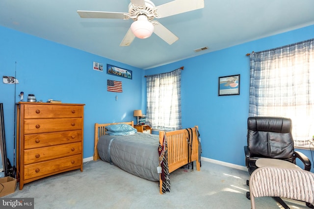 carpeted bedroom with visible vents, baseboards, and a ceiling fan