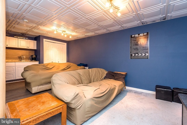 living room with carpet flooring, indoor wet bar, an ornate ceiling, and baseboards