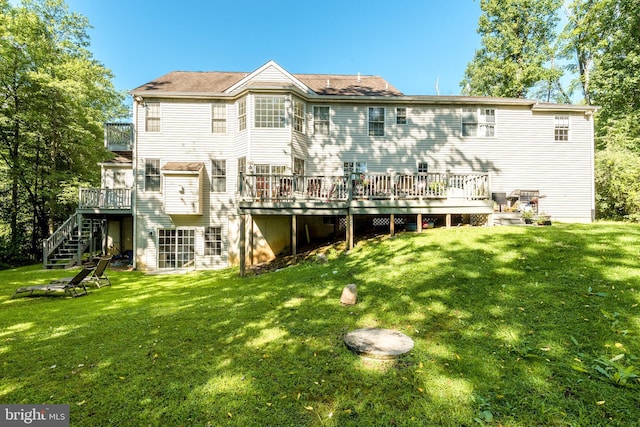 back of house featuring a wooden deck, a lawn, and stairs