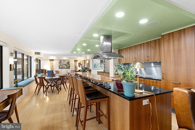 2001 Hamilton St Unit 1914, Philadelphia, PA 19130 - kitchen featuring island range hood, open floor plan, brown cabinetry, light wood-style floors, and recessed lighting