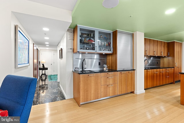 2001 Hamilton St Unit 1914, Philadelphia, PA 19130 - kitchen featuring glass insert cabinets, brown cabinets, dark countertops, light wood finished floors, and recessed lighting