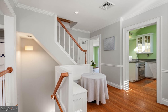 staircase featuring crown molding, visible vents, recessed lighting, wood finished floors, and baseboards