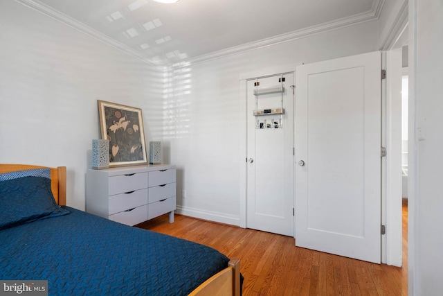 bedroom with light wood-style floors and crown molding