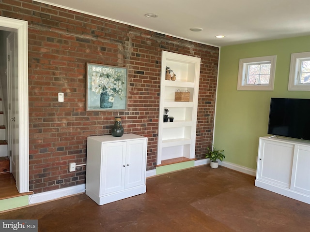 interior space featuring built in shelves, baseboards, brick wall, recessed lighting, and finished concrete floors