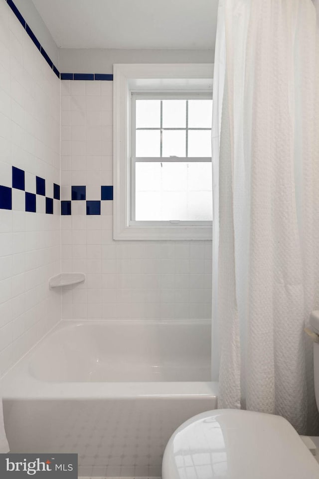 full bathroom featuring shower / bath combo with shower curtain and toilet