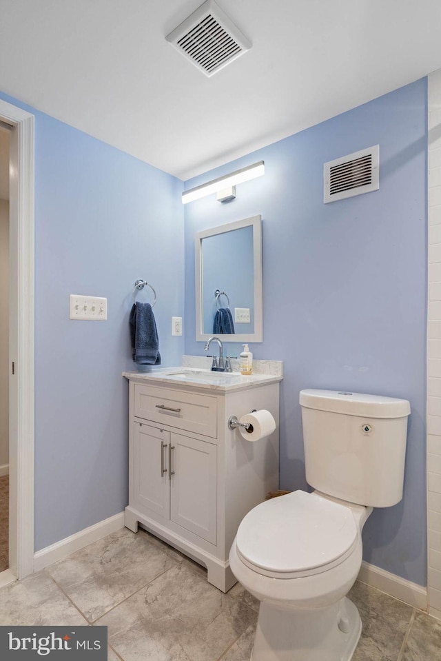 bathroom featuring toilet, vanity, baseboards, and visible vents